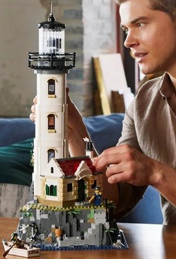 Image of the Lego Ideas Motorized Lighthouse being built by a man on a table top nearing completion of the set